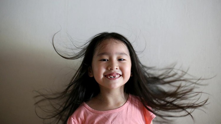 An Asian girl is feeling cheerful with her long and wavy hair.