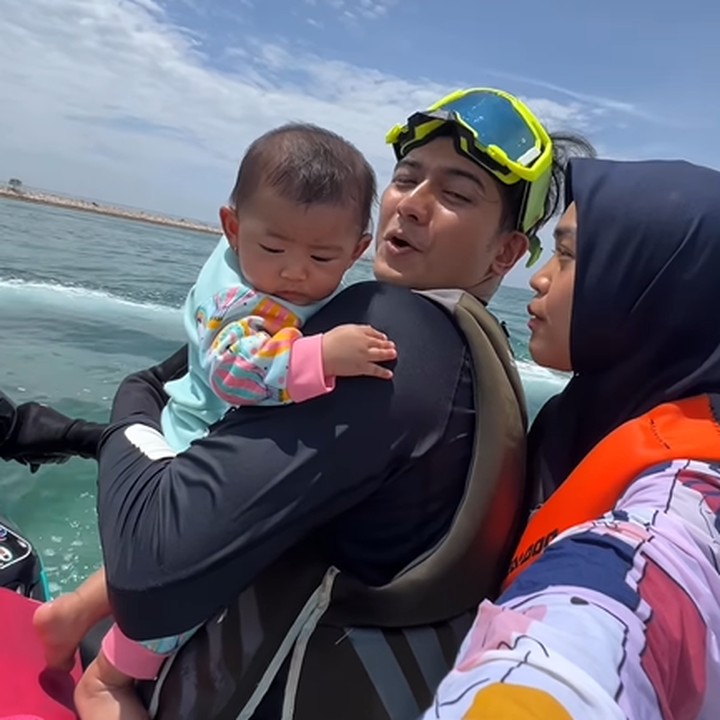 <p>Setelah memangku Moana di tengah, Ria Ricis kemudian memindahkan posisi sang putri ke depan. Ia digendong dengan memakai satu tangan oleh Teuku Ryan. Aduh anteng banget dia. Guys ini pertama kali Moana naik jetski. Rambutnya terbang-terbang," kata Ricis. (Foto: Instagram @riaricis1795)</p>