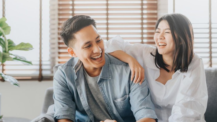 1191552785 Happy Asian couple having fun and laughing together in living room at home