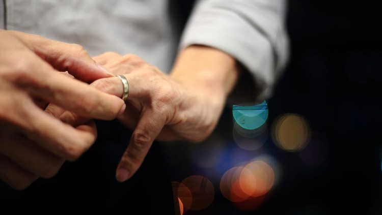 man putting on wedding ring. close up shot of man fidgeting ring with nice out of focus urban light backgrounds.