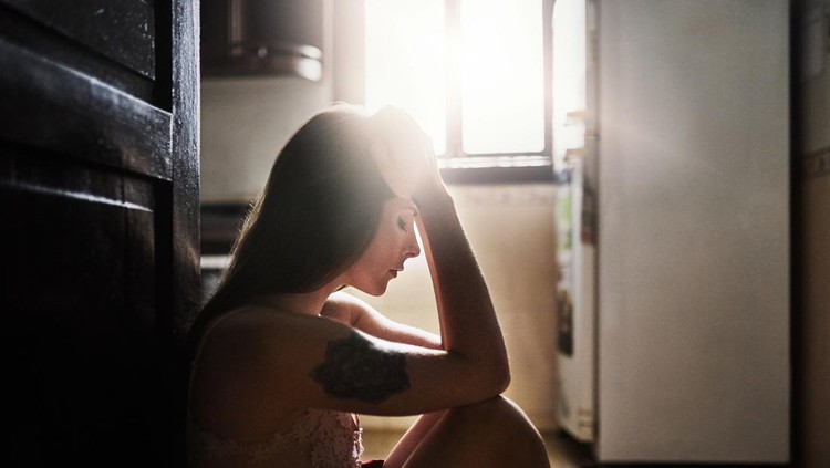 Shot of an attractive young woman sitting down and feeling depressed inside her apartment