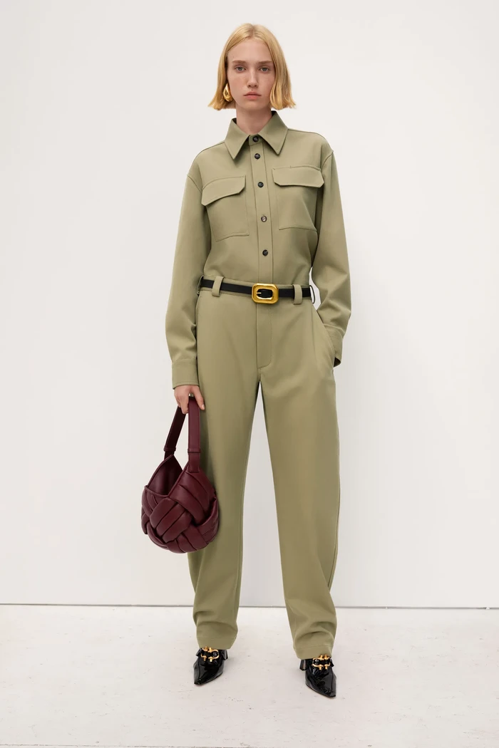 Safari shirt dihadirkan sebagai opsi gaya boyish. Pulasan warna khaski dan tas bucket yang terinspirasi helm menampilkan total look yang modern dan quirky. Foto: Courtesy of Bottega Veneta