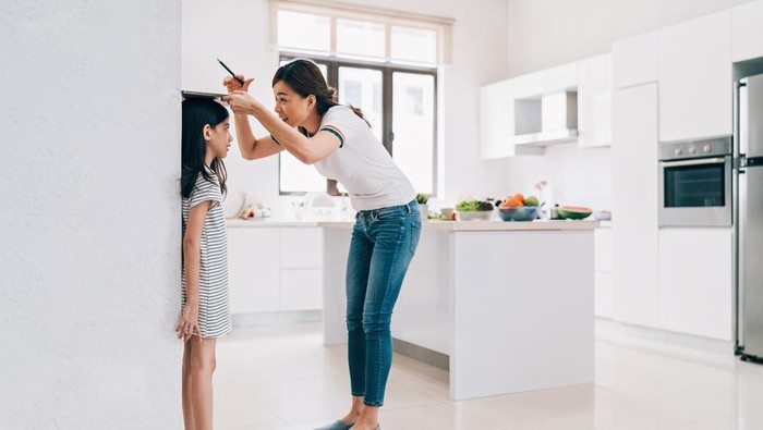 mother measuring height of her son