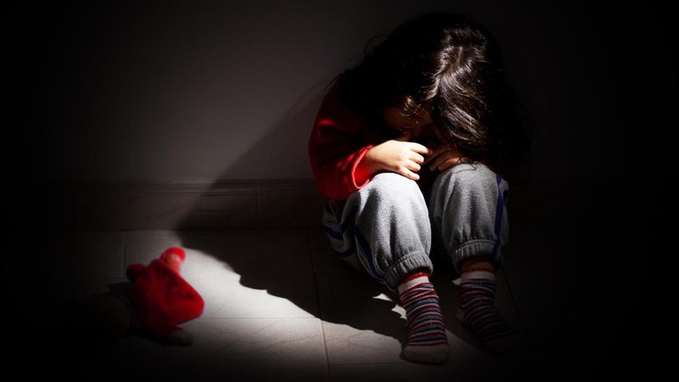 young girl sitting down alone in the dark.