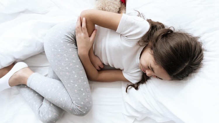 Ilustrasi Pertolongan Pertama pada Anak Sakit The girl has a stomach ache. She feels bad and uncomfortable, then that it hurts. She holds her hands in her sore spot.