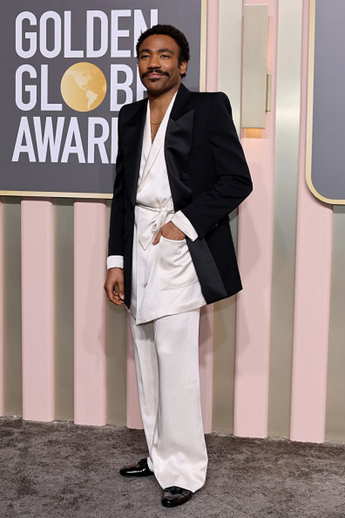 Donald Glover menghadirkan kombinasi piyama putih dan jas oversized menciptakan tampilan klasik yang eklektik. Busana tersebut merupakan kreasi Saint Laurent. Foto: Getty Images/Amy Sussman
