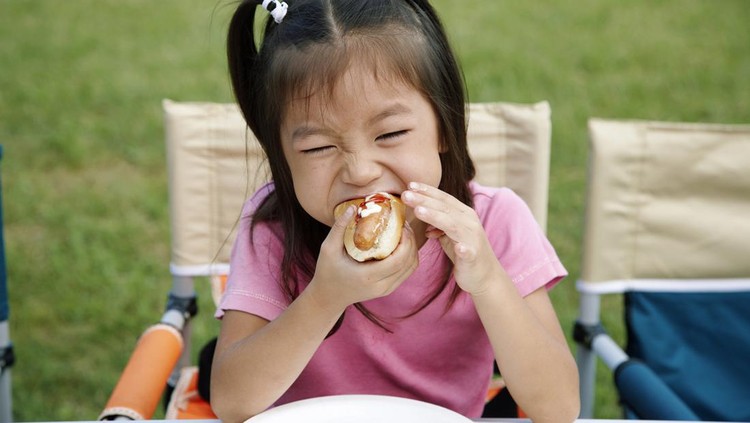 Asian Little Chinese Girl eating hamburger in the outdoor cafe