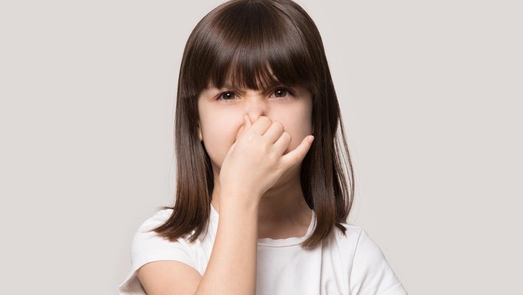 Close up head shot portrait image with shocked little girl. Concept unhappy kid feeling bad and dislike smell and hold nose from funny odor, stinky on gray background, six year child looking at camera