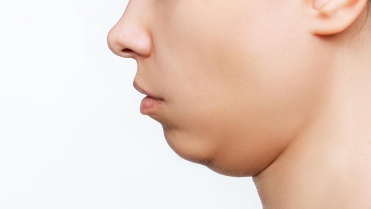 Cropped shot of a young caucasian woman's face with double chin isolated on a white background. Overweight, flabby and sagging skin. Profile
