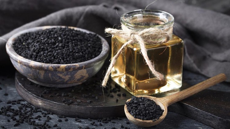 1353988466 Black seeds in a bowl and oil on a black background