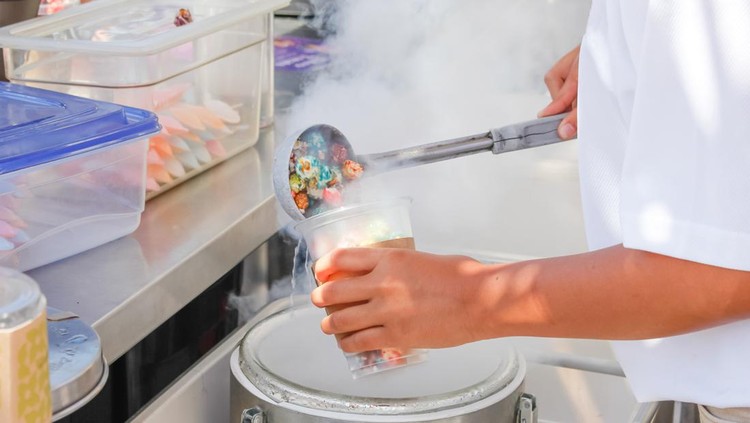 Ilustrasi Chiki Ngebul A view of an employee preparing a cup of dragon's breath cereal dessert at a food stand.