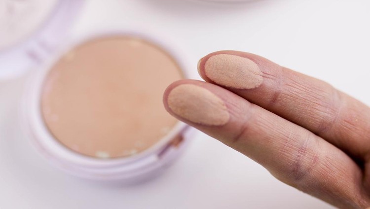 1207451097 Swatches of powder palette on a woman's fingers. Isolated on white background.
