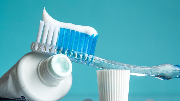 New toothbrush with toothpaste close-up in the bathroom on a mirror table with water drops on a blue background in the sunlight