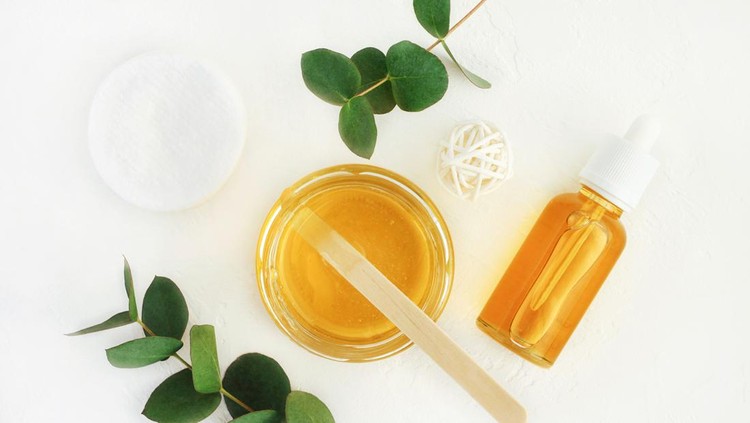 Yellow jars and bottle of facial mask top view with leaves white background