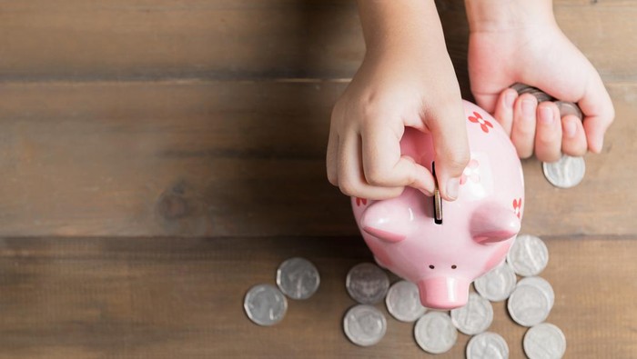 kid put coin to piggy bank on the vintage wood background, a saving money for future education concept and copy space for input text.
