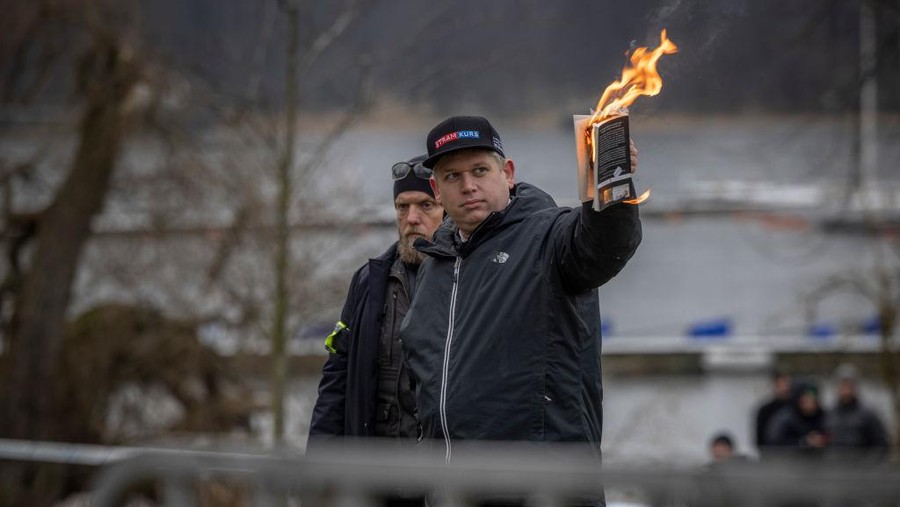 STOCKHOLM, SWEDEN - JANUARY 21: Rasmus Paludan burns the Koran outside of the Turkish embassy on January 21, 2023 in Stockholm, Sweden. Swedish authorities granted permission to a series of protests for and against Turkey amid the bid to join NATO, with far-right Danish-Swedish politician Rasmus Paludan - a controversial figure in Sweden - set to stage a Koran burning outside the Turkish embassy, as well as pro-Erdogan and pro-Kurdish groups protesting simultaneously. (Photo by Jonas Gratzer/Getty Images)