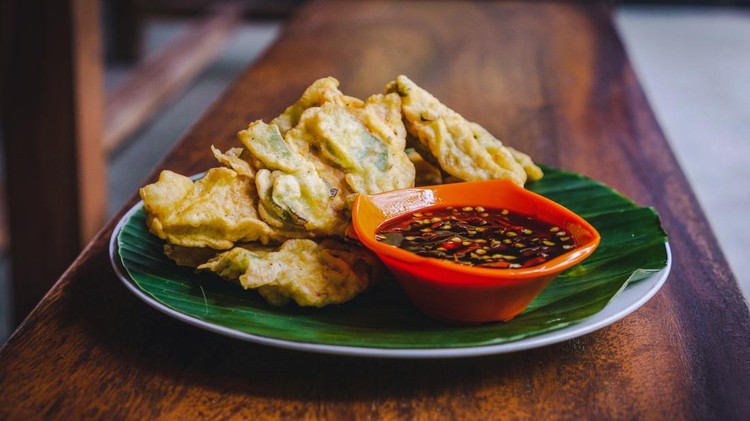 Side and top view of stock photos fried tempeh, with spicy sweet bean sauce served on banana leaves on the plate and served on wooden table. One of the menu in the Indonesian small restaurant or street food.