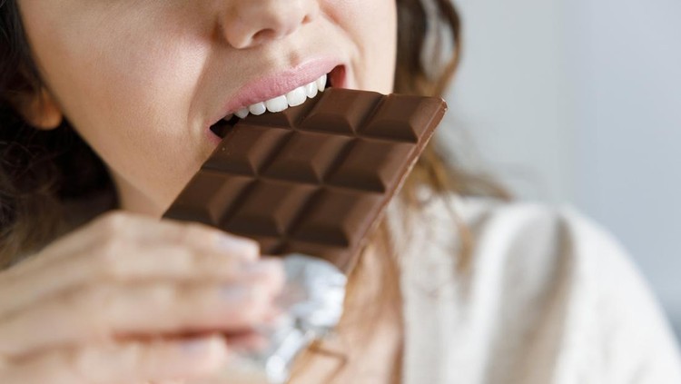 Young woman eating chocolate at home