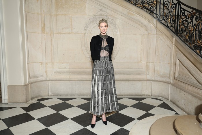 Pemeran Putri Diana di serial The Crown, Elizabeth Debicki memilih gaya kasual feminin lewat jaket, blus transparan, dan rok lipit A-line. Foto: Courtesy of Dior