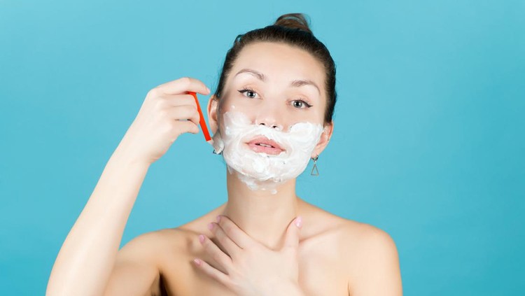 1217327780 girl shaving her face with a disposable razor using shaving foam. Close up