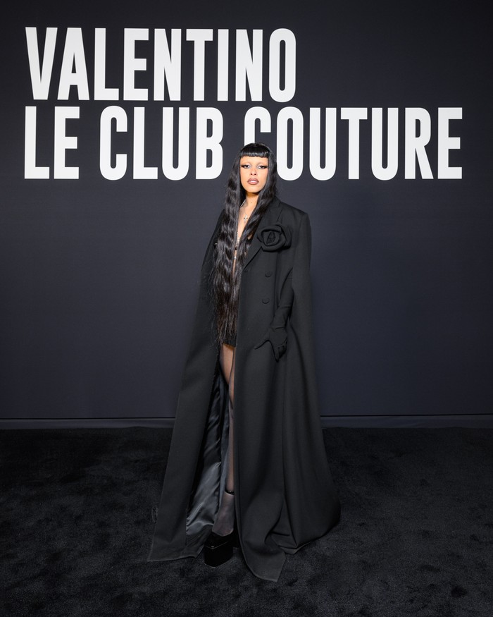 Doja Cat kembali menunjukkan eksplorasi gaya. Kali ini tampak mengusung tema gothic nan seksi lewat kombinasi mantel aksen corsage, bralette, dan rok. Foto: Valentino/SGPItalia