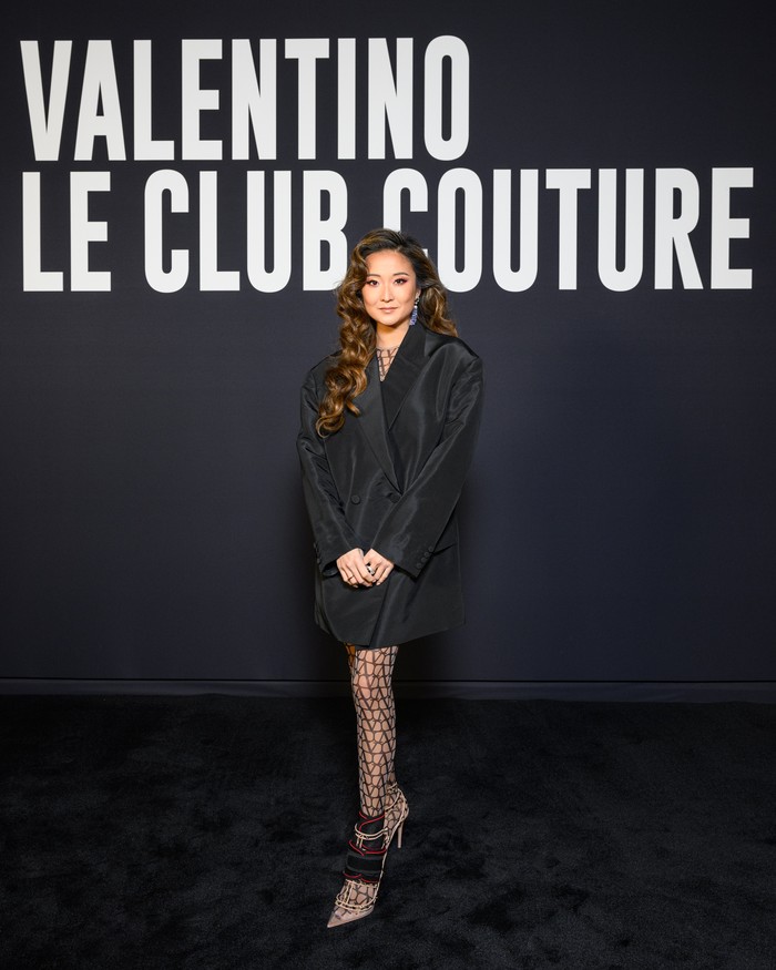 Ashley Park terlihat bergaya klasik dan feminin dalam oversized tuxedo dress dengan stocking logo Valentino. Foto: Valentino/SGPItalia
