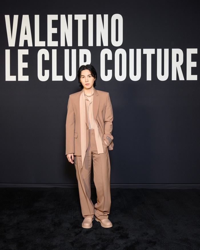 Suga membuktikan bahwa bergaya stylish dalam setelan jas bagi pria tak harus dalam warna hitam. Tapi bisa juga memilih rona earth tone atau nude. Foto: Valentino/SGPItalia