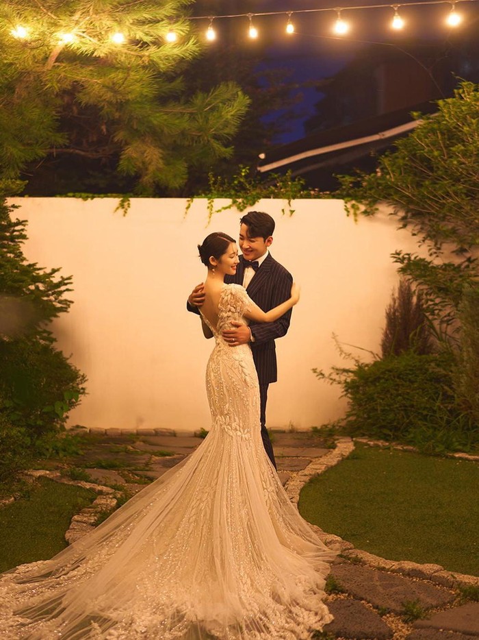 Yukika tampak anggun dengan mermaid wedding dress warna putih yang menjuntai panjang, serta Minhyuk MAP6 yang tampak gagah dengan tuxedo hitam miliknya./ Foto: soompi.com