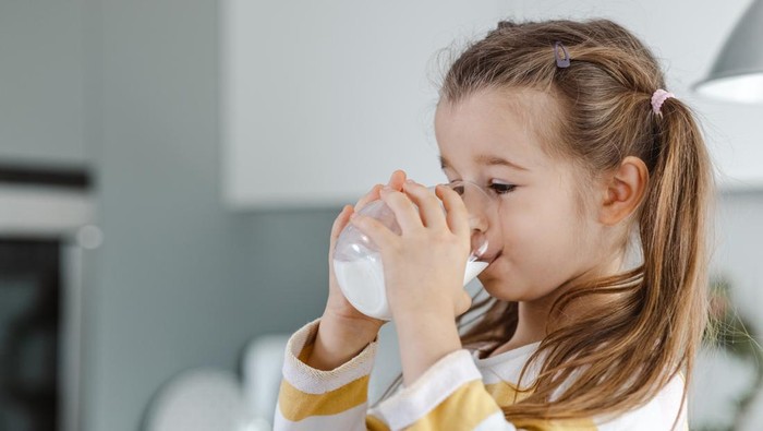 5 years old girl holding glass of milk