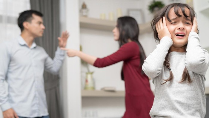 Sadness little girl against blured of mother and father with quarrel at home.