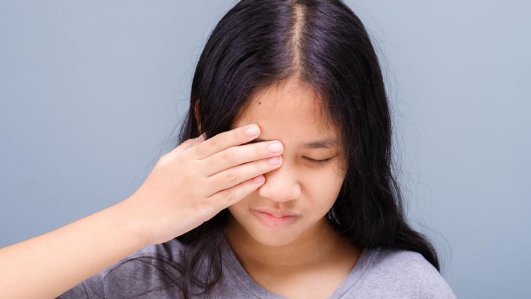 Eleven years old girl has a problem with her eye, suffering from irritation, and try to cover it with her hand