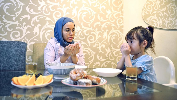Ilustrasi Anak Belajar Berpuasa Young asian daughter eating with mother in the kitchen
