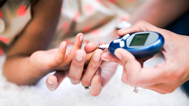 Mother is checking her daughters' diabetes by monitoring blood glucose.