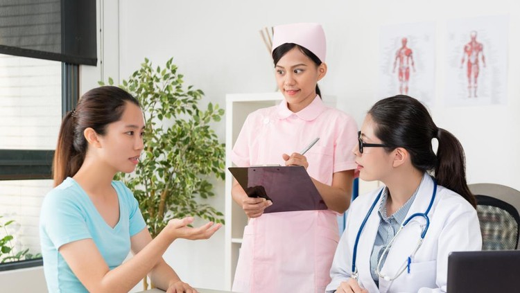 1015398986 beautiful young nurse standing in office writing medical record on noteboard when patient illustrating personal sick problem for doctor.