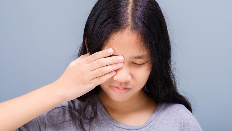 Eleven years old girl has a problem with her eye, suffering from irritation, and try to cover it with her hand