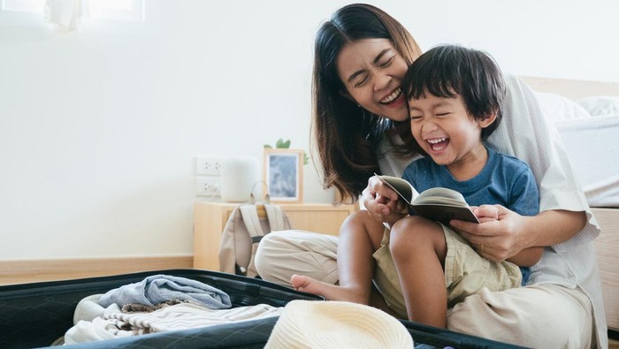 Young asian woman and little baby boy preparing for road trip at home.