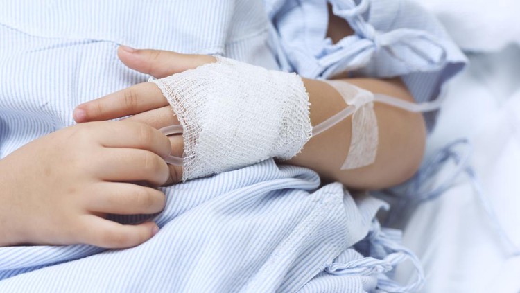 Ilustrasi Deteksi Dini Kanker pada Anak Hand of the sick child with saline solution with Space for text.