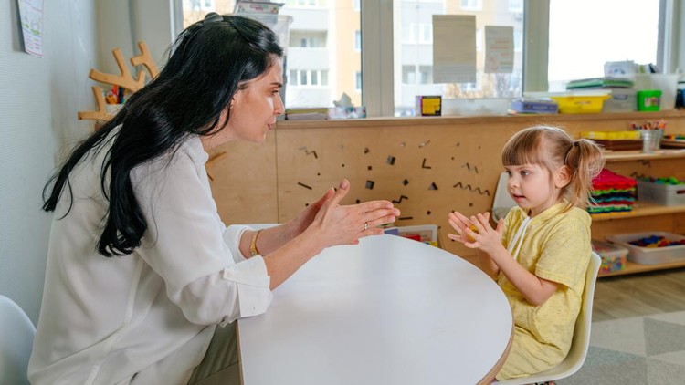 Little girl on the lesson of the development of fine motor skills in kindergarten. Playing with fingers massager as an activity for toddlers to expand sensory perception and speech skills.