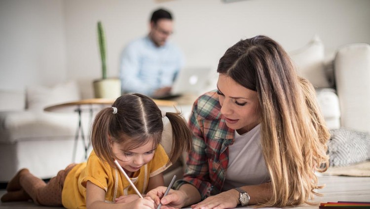Getting help with my tasks. Little girl working her homework with mother. Focus is on foreground.