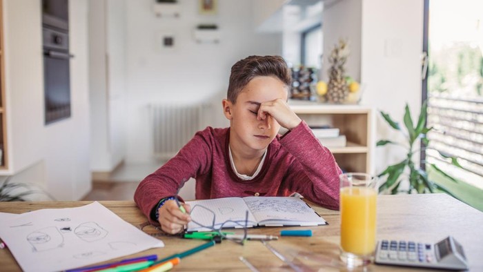 One man, young boy is tired of doing homework, sitting at the table.