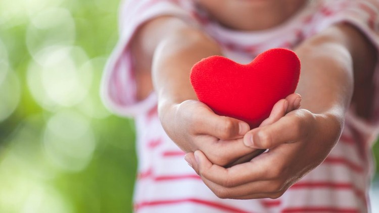 Cute asian little child girl showing and holding red heart in hand with care and love
