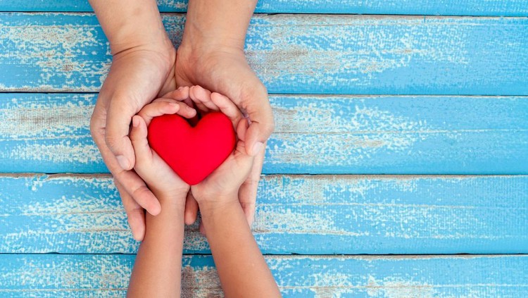 Cute asian little child girl showing and holding red heart in hand with care and love