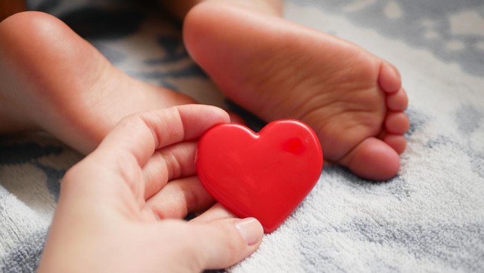mother holds heart on the background of a small child.