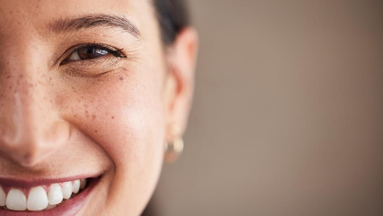 Face of beautiful mixed race woman smiling with white teeth.  Portrait of a woman's face with brown eyes and freckles posing with copy-space. Dental health and oral hygiene