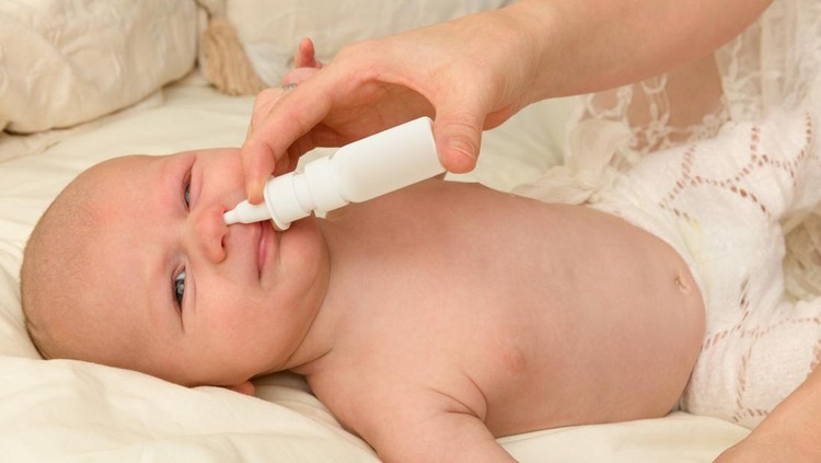 Little 7 week old baby getting nose drops by his mom