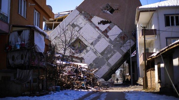 Sepekan Gempa Turki-Suriah, Korban Tewas Tembus 36.000 Orang A man walks near a building that leans on a neighbouring house in Golbasi, Turkey, Monday, Feb. 13, 2023. Thousands left homeless by a massive earthquake that struck Turkey and Syria a week ago packed into crowded tents or lined up in the streets for hot meals Monday, while the desperate search for anyone still alive likely entered its last hours. (AP Photo/Francisco Seco)