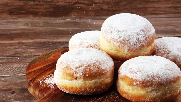 German donuts with jam and icing sugar. Carnival powdered sugar raised donuts.