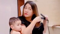 <p>Vicky Shu selalu bisa membagi waktu antara menjaga sang anak dengan pekerjaan, Bunda. Di salah satu posting-annya, Vicky bahkan bisa menggendong sang anak dengan kain jarik sekaligus mencatok rambut. (Foto: Instagram: @vickyshu)</p>