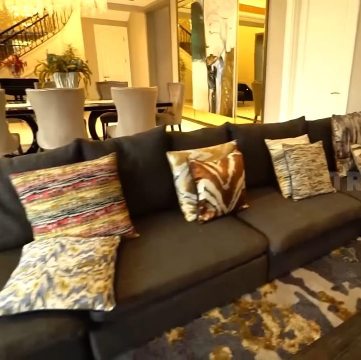 <p>Menyusuri area ruang keluarga yang tak ada sekat dengan meja makannya. Untuk ruang keluarga, Vio menambahkan sofa dengan warna gelap dan dilenkapi beberapa bantal dengan motif yang cukup unik. (Foto: YouTube TRANS7 OFFICIAL)</p>