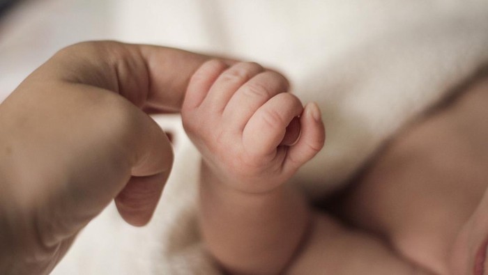 child hand squeezes adult finger, holding mother's hand.  The concept of empathy, trust, care and tenderness of motherhood. blurred background